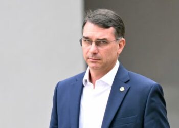 Flávio Bolsonaro 2026: A Escolha De Jair Bolsonaro Para Disputar A Presidência E Reorganizar A Direita Brasileira A Decisão Anunciada Por Jair Bolsonaro Dentro Da Superintendência Da Polícia Federal, Em Brasília, Reorganizou De Forma Imediata O Cenário Político E As Expectativas Da Direita Para O Próximo Ciclo Eleitoral. Em Meio À Prisão Do Ex-Presidente E Às Incertezas Sobre Sua Participação Direta Na Arena Política, O Nome Escolhido Para Representá-Lo Nas Urnas É O Do Primogênito, Senador Flávio Bolsonaro (Pl-Rj). A Confirmação, Feita Pessoalmente Durante Uma Visita Do Parlamentar Ao Pai, Passa A Reposicionar Todo O Tabuleiro Da Oposição E Inaugura A Fase Mais Decisiva Da Estratégia Eleitoral Bolsonarista Para 2026. Desde O Primeiro Momento Em Que A Informação Chegou À Cúpula Do Pl, Dirigentes E Aliados Compreenderam Que A Escolha Vai Além De Uma Preferência Familiar. Representa Uma Tentativa Explícita De Manter A Força Política De Jair Bolsonaro Ativa, Preservando Seu Capital Eleitoral Por Meio Do Nome Mais Orgânico Disponível Entre Seus Herdeiros. A Decisão Também Encerra Meses De Especulações Sobre Diversos Nomes Que Poderiam Ocupar Essa Vaga — De Michelle Bolsonaro Ao Governador De São Paulo, Tarcísio De Freitas — Consolidando O Senador Como O Rosto Do Projeto Político Do Bolsonarismo No Próximo Ciclo Nacional. A Partir Dessa Sinalização Formal, Emerge O Desafio Central: Construir A Competitividade De Flávio Bolsonaro 2026 Em Um Ambiente Polarizado, Desgastado E Marcado Pela Pressão Institucional. Ao Assumir O Protagonismo Eleitoral, O Senador Terá De Unir A Base Bolsonarista, Intensificar Viagens, Articular Palanques Estaduais E Enfrentar Disputas Internas, Ao Mesmo Tempo Em Que Administra O Impacto Político Da Prisão Do Pai. Essa Tarefa Inaugura Um Período De Definições Para A Direita E Exige Habilidade Estratégica Para Garantir Que A Narrativa Do Campo Bolsonarista Permaneça Coesa Até A Eleição. A Comunicação Pública Da Decisão E O Simbolismo Político De Flávio Bolsonaro 2026 O Anúncio Da Escolha Tornou-Se Público Quando Flávio Bolsonaro Utilizou As Redes Sociais Para Revelar A “Missão” Recebida Do Pai. Em Uma Declaração Carregada De Elementos Religiosos E Políticos, O Senador Afirmou Que Lhe Caberia “Dar Continuidade Ao Projeto De Nação” Defendido Por Jair Bolsonaro. O Texto Reforçou A Ideia De Legado, Continuidade E Responsabilidade Histórica, Conceitos Mobilizados Para Fortalecer Sua Imagem Dentro Da Base Conservadora. A Publicação Gerou Intensa Repercussão. O Uso De Uma Narrativa Mística — Ao Dizer Que Estaria “Diante De Deus E Diante Do Brasil” — Demonstra A Estratégia De Reforçar Um Vínculo Emocional Com O Eleitorado Mais Fiel Ao Bolsonarismo. Esse Grupo, Que Permanece Mobilizado Mesmo Diante Das Adversidades Jurídicas Do Ex-Presidente, É Fundamental Para Sustentar A Candidatura De Flávio Bolsonaro 2026 Nos Primeiros Meses Da Pré-Campanha. Ao Mesmo Tempo, Dirigentes Do Pl Afirmam Que A Comunicação Pública Foi Combinada Previamente E Representa Um Passo Calculado. A Intenção É Ocupar Imediatamente O Espaço De Discussão Política, Evitar Lacunas Estratégicas E Impedir Que Eventuais Divisões Internas Se Ampliem. A Diretriz De Bolsonaro: Viagens, Combatividade E Articulação Partidária Segundo Relatos De Integrantes Da Cúpula Do Pl, A Orientação De Jair Bolsonaro Ao Filho Inclui Três Eixos Principais. O Primeiro É Intensificar Viagens Por Todo O País. O Segundo É Marcar Presença Nos Eventos Da Sigla E Nos Encontros Com Lideranças Regionais. O Terceiro É Adotar Uma Postura Mais Combativa Em Relação Ao Presidente Luiz Inácio Lula Da Silva, Especialmente Em Temas Econômicos, Segurança Pública E Políticas De Costumes. A Estratégia É Clara: Tornar O Nome De Flávio Bolsonaro 2026 Uma Presença Constante Na Imprensa, Nos Movimentos Partidários E Nas Bases Conservadoras. A Campanha, Embora Ainda Informal, Já Começou A Ser Estruturada Por Aliados Que Tratam Esse Período Como Essencial Para Sedimentar O Nome Do Senador Como O Candidato Oficial Da Direita Tradicional. A Expectativa É Que, A Partir Do Início De 2025, Flávio Assuma O Protagonismo Público E Ocupe Os Palanques Estaduais Que Antes Eram Reservados Ao Pai. A Missão Inclui Negociar Alianças, Reconciliar Divergências Internas E Fortalecer A Musculatura Eleitoral Do Pl. As Tensões Internas E O Episódio Com Michelle Bolsonaro A Escolha Do Senador Também Ocorre Em Meio A Um Episódio Que Expôs Divergências Internas. Michelle Bolsonaro Venceu Uma Disputa Por Alianças Políticas No Ceará, O Que Provocou Atritos Com Flávio. A Disputa Revelou Uma Divisão Silenciosa Entre Duas Frentes Importantes Do Bolsonarismo: A Institucional, Liderada Por Flávio, E A Carismática, Representada Por Michelle. Embora Dirigentes Neguem Uma Ruptura, Aliados Reconhecem Que O Episódio Deixou Marcas E Influenciou O Cálculo Político Do Próprio Jair Bolsonaro. Segundo Relatos, Ele Avaliou Que Flávio Reunia Maior Capacidade De Articulação Junto À Classe Política, Enquanto Michelle, Apesar De Seu Apelo Popular, Teria Dificuldades Estruturais Para Comandar Negociações Complexas Nos Estados. A Consolidação De Flávio Bolsonaro 2026, Portanto, Exige Superar Essas Tensões E Integrar Diferentes Alas Do Bolsonarismo. Para Isso, O Senador Precisará Equilibrar Discurso Ideológico, Articulação Institucional E Presença Territorial — Uma Equação Complexa Para Qualquer Pré-Candidato. Como A Escolha De Flávio Reorganiza A Direita Até O Anúncio Formal, O Nome Mais Cotado Para Representar A Direita Era O De Tarcísio De Freitas, Governador De São Paulo. Considerado Tecnicamente Competente E Popular Em Setores Específicos, Tarcísio Era Tratado Como Alternativa Natural Caso Bolsonaro Estivesse Inelegível Em 2026. No Entanto, O Governador Já Havia Sinalizado Que Deseja Concluir Seu Mandato E Não Cogitava Ocupar O Posto De Vice. Essa Posição Abriu Espaço Para Jair Bolsonaro Fortalecer Sua Preferência Pelo Filho. O Cálculo É Simples: Um Candidato Com Laços Diretos Com Bolsonaro Tem Maior Facilidade Para Herdar Sua Base Eleitoral, Enquanto Outro Nome Teria De Conquistá-La Gradualmente. A Escolha Por Flávio Reorganiza A Direita Em Três Eixos: O Pl Assume O Comando Formal Do Projeto Eleitoral De 2026, Consolidando-Se Como O Principal Polo Político Da Direita Tradicional. O União Brasil, Republicanos E Outros Partidos Conservadores Precisarão Se Posicionar, Seja Para Apoiar Flávio, Seja Para Construir Alternativas. O Governador Tarcísio De Freitas Passa A Ocupar Um Papel De Liderança Regional, E Não Nacional, Ao Menos Até O Encerramento De Seu Mandato. Essa Reorganização Cria Um Novo Mapa Para As Disputas Estaduais E Fortalece O Eixo Rio–Brasília Na Articulação Bolsonarista. O Desafio De Transformar Flávio Bolsonaro 2026 Em Um Nome Nacional Embora Seja Figura Conhecida No Cenário Político, Flávio Enfrenta Uma Dificuldade Natural: Seu Alcance Nacional É Menor Que O Do Pai E Que O De Outras Lideranças Emergentes Da Direita. Por Isso, A Pré-Campanha Deve Investir Fortemente Na Construção De Sua Imagem Em Três Frentes Diferentes. 1. Proximidade Emocional Com O Eleitorado De Bolsonaro A Narrativa Do “Herdeiro Político” Está Sendo Cuidadosamente Moldada Para Mostrar Continuidade De Valores, Princípios E Identidade. 2. Capacidade De Negociação E Articulação Dirigentes Do Pl Enfatizam Que O Senador É Considerado Mais Habilidoso Do Que O Pai Na Interlocução Com Setores Institucionais E Econômicos. 3. Postura Combativa E Firme Para Atrair A Base Mais Ideológica, Flávio Terá De Reforçar Críticas Ao Governo Lula E Se Posicionar De Forma Incisiva Em Debates Centrais. Essa Tríade Será Decisiva Para Que Flávio Bolsonaro 2026 Se Consolide Como Nome Viável No Primeiro Turno. Impacto Da Prisão De Jair Bolsonaro Na Estratégia Eleitoral A Prisão Do Ex-Presidente É Fator Determinante Para Compreender O Movimento Político Atual. Dentro Da Pf, Bolsonaro Mantém Contato Limitado, Mas Orienta Aliados E Acompanha O Cenário. A Decisão De Escolher O Filho Como Sucessor Político É, Ao Mesmo Tempo, Simbólica E Prática. Simbólica, Porque Transmite A Ideia De Continuidade E Resiliência. Prática, Porque Garante Que Um Nome De Sua Confiança Conduzirá O Projeto Bolsonarista. A Defesa De Bolsonaro, Por Sua Vez, Acredita Que Flávio Poderá Fortalecer A Narrativa De Perseguição E Reforçar O Vínculo Emocional Entre O Ex-Presidente E Sua Base. Essa Leitura Já Está Presente Nos Discursos De Aliados E Deve Ser Intensificada Ao Longo Dos Próximos Meses. A Pré-Campanha Começa Agora Dirigentes Do Pl Afirmam Que A Ordem É Clara: Flávio Precisa Intensificar Agendas, Viagens E Articulações A Partir Deste Mês. O Partido Estruturará Equipes Regionais E Ampliará Eventos De Mobilização Já No Primeiro Trimestre De 2026. O Objetivo É Consolidar O Nome De Flávio Bolsonaro 2026 Antes Mesmo Da Construção Formal Dos Blocos Partidários. A Principal Meta Do Pl É Garantir Que O Senador Se Torne O Candidato Natural Da Direita Antes Que Outras Legendas Formem Alternativas Robustas. Com Isso, A Cúpula Evita Divisões Internas E Fortalece O Protagonismo Do Bolsonarismo Na Próxima Eleição Presidencial. Conclusão: A Direita Entra Em Sua Fase Mais Decisiva Rumo A 2026 A Escolha De Jair Bolsonaro Por Flávio Como Seu Sucessor Eleitoral Inaugura Um Novo Capítulo Na Direita Brasileira. Representa Não Apenas A Continuidade De Um Projeto Político, Mas Também O Reconhecimento De Que O Bolsonarismo É, Hoje, Um Movimento Que Precisa Se Reorganizar Diante Dos Desafios Institucionais Enfrentados Pelo Ex-Presidente. Ao Assumir Esse Papel, Flávio Bolsonaro 2026 Torna-Se O Epicentro De Uma Disputa Complexa Que Envolve Alianças Regionais, Narrativas Nacionais, Articulações Partidárias E A Necessidade De Unir Diferentes Alas Dentro De Um Mesmo Campo Político. Seu Desempenho Nos Próximos Meses Será Determinante Para Definir O Rumo Da Próxima Eleição Presidencial E O Futuro Do Bolsonarismo No Brasil. - Gazeta Mercantil - Política