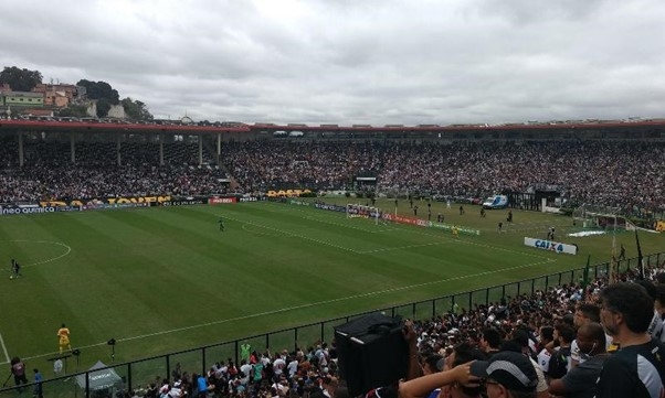 Foto Do Estádio São Januário, No Rio De Janeiro, Com As Arquibancadas Lotadas E Mostrando Uma Das Metades Do Campo, Em Que Constam Um Goleiro E Um Jogador De Linha Prestes A Atravessar O Meio De Campo - Gazeta Mercantil